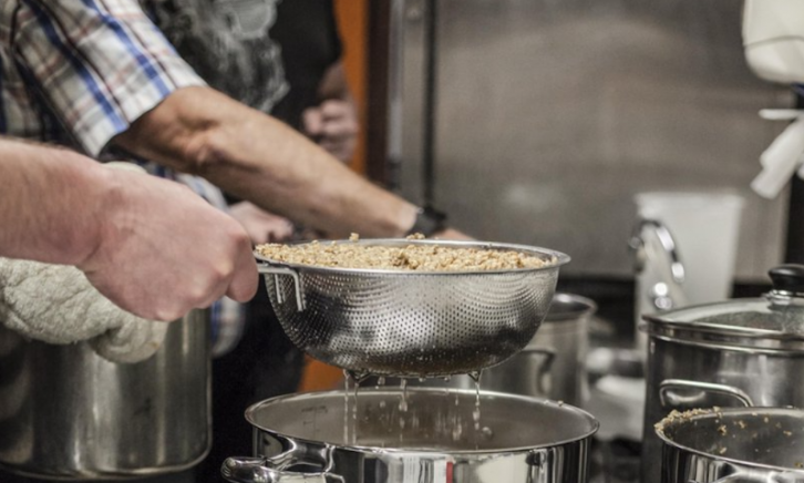 Zelf bier aan het brouwen: mout met een vergiet uit de pan vissen